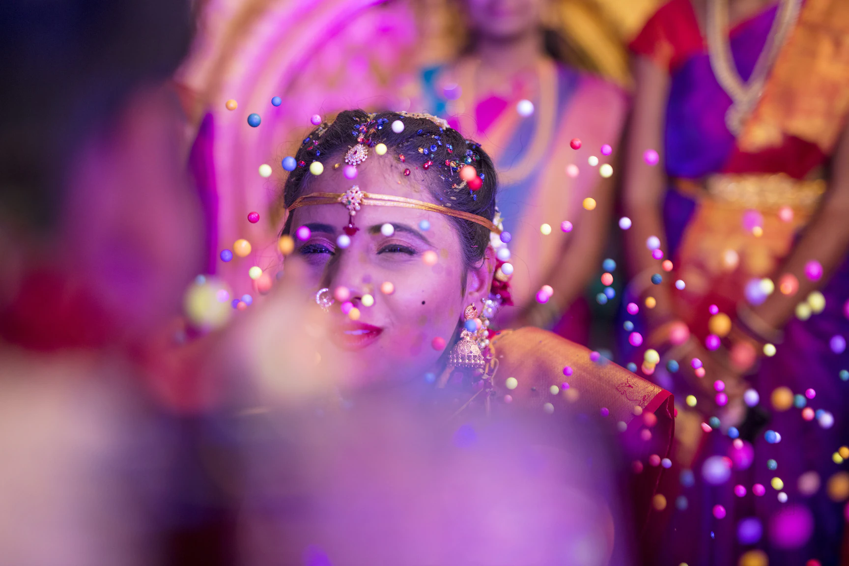 Bride smiling through a shower of colourful confetti at a Hyderabad wedding