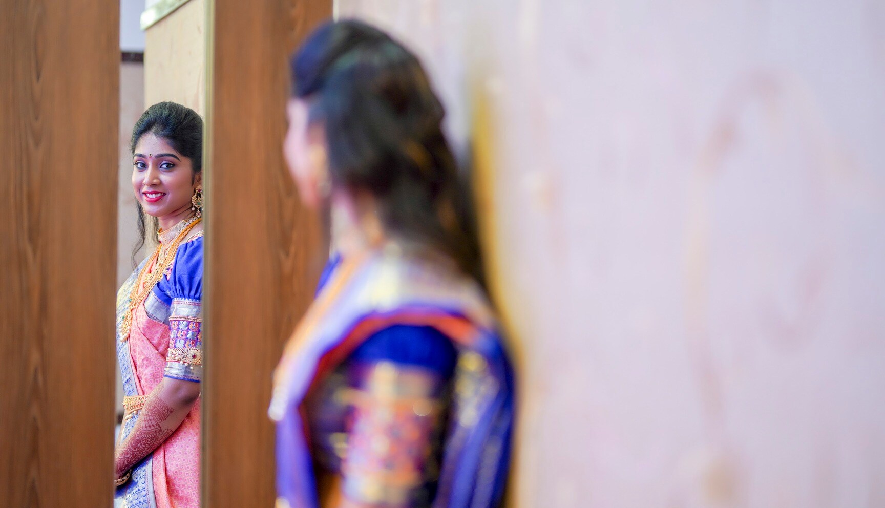 Telugu bride in a peach and blue silk saree looking at her reflection before the muhurtham, Hyderabad wedding